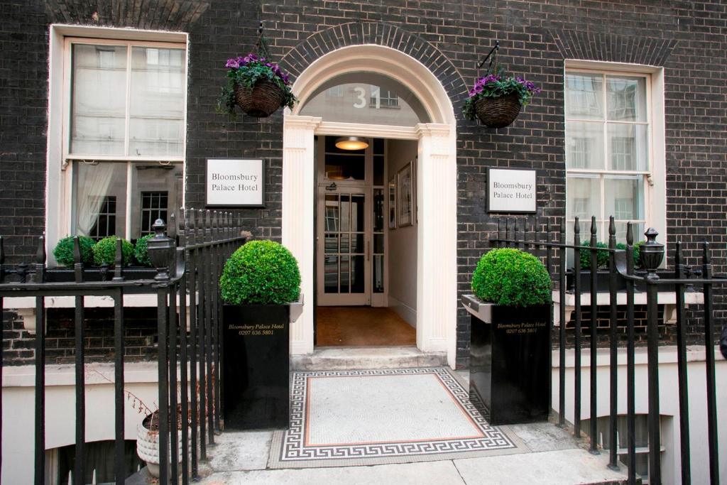 une porte d'entrée d'un bâtiment en briques avec des plantes dans l'établissement Bloomsbury Palace Hotel, à Londres