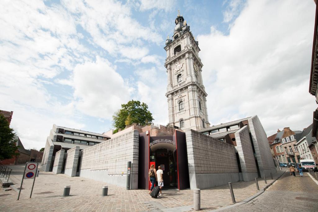 un bâtiment avec une tour d'horloge en haut dans l'établissement Auberge de Jeunesse de Mons, à Mons