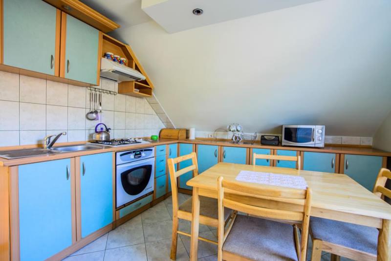 een keuken met blauwe kasten en een tafel en stoelen bij Apartament u Zosi Krościenko in Krościenko