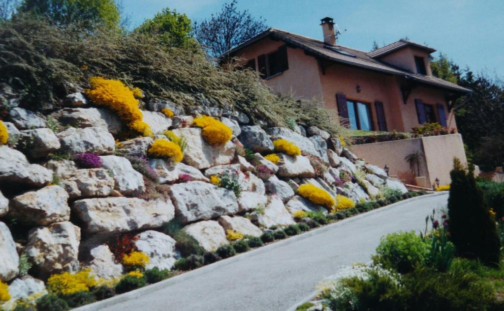 a stone wall next to a house with flowers at Les Roches Fleuries in Prunières