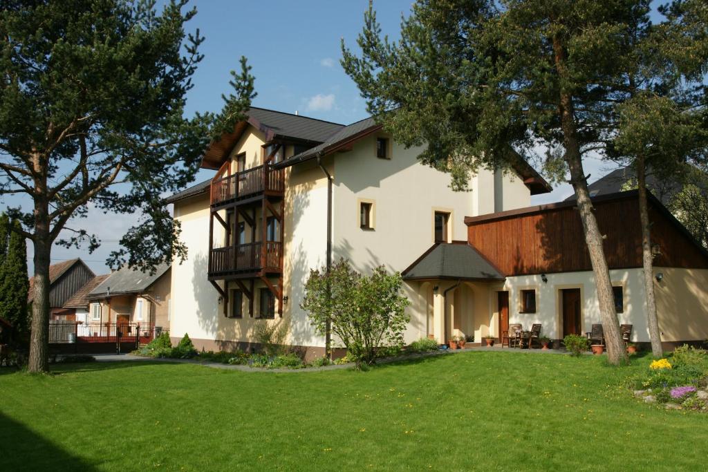 una grande casa bianca con un cortile verde di Guest House Boba a Štrba