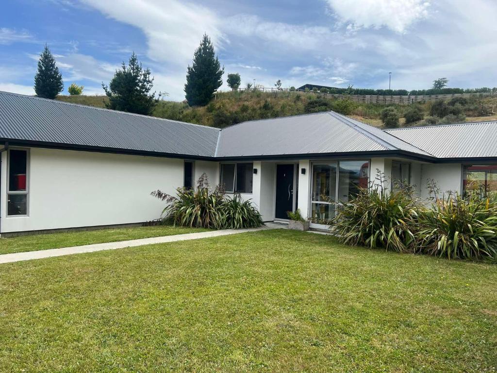 a white house with a grass yard at Luxury Ludemann Lodge Apartment in Queenstown