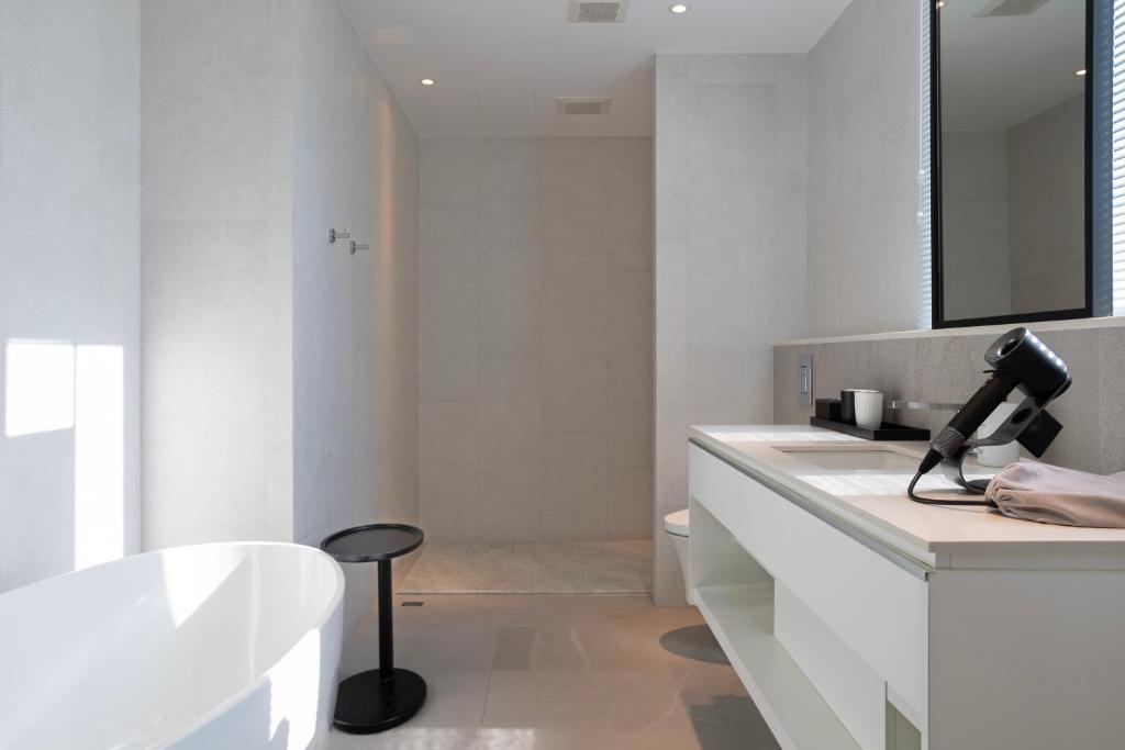 a white bathroom with a tub and a sink at Manho Hotel in Taichung