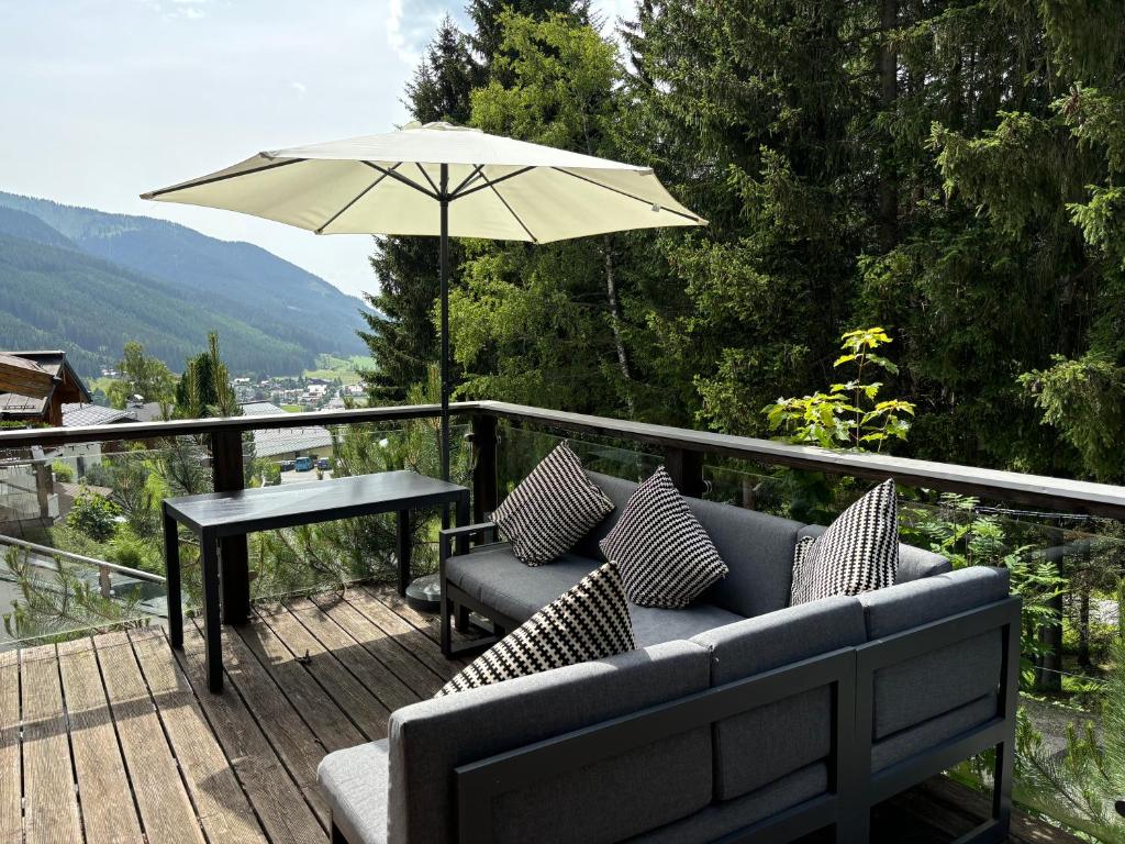 a patio with a couch and a table and an umbrella at Luxury Filzmoos Chalet in Filzmoos