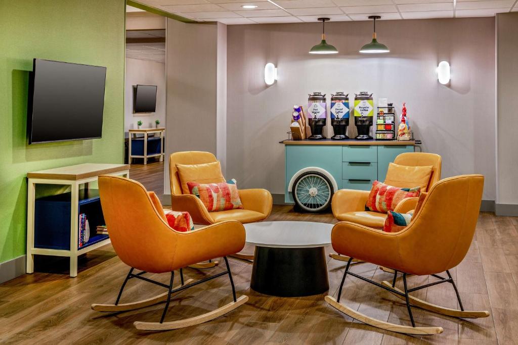 a waiting room with chairs and a table and a tv at Spark by Hilton Denver International Airport in Denver