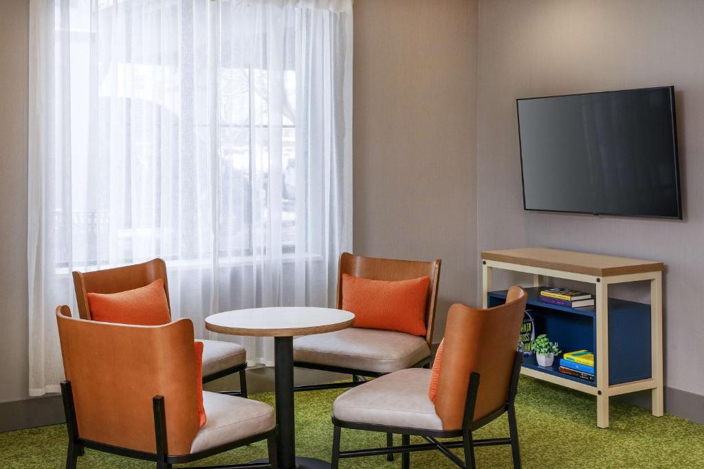 a room with chairs and a table and a tv at Spark by Hilton Denver International Airport in Denver
