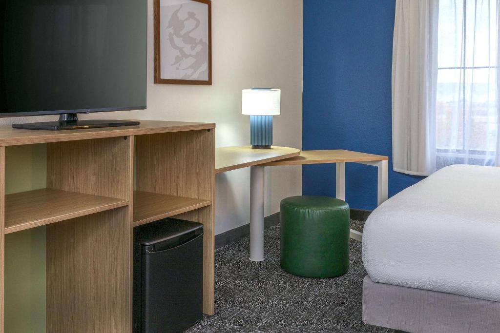 a room with a bed and a desk with a television at Spark by Hilton Denver International Airport in Denver