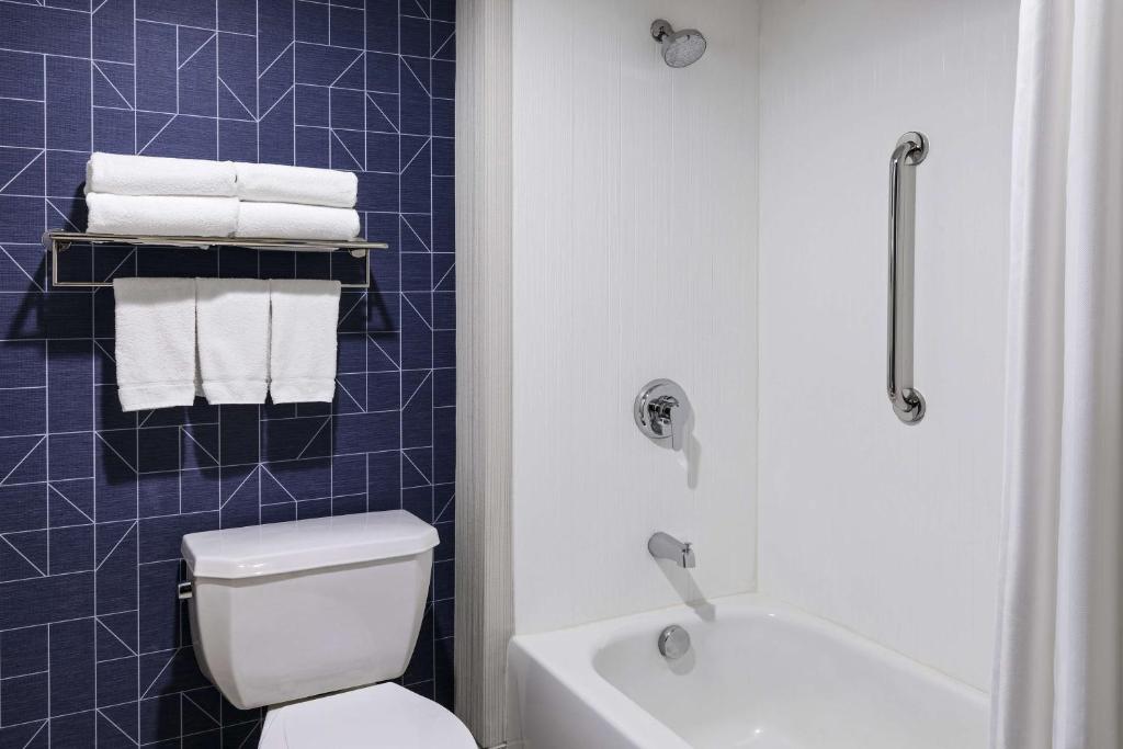 a bathroom with a white toilet and a blue tiled wall at Spark by Hilton Denver International Airport in Denver