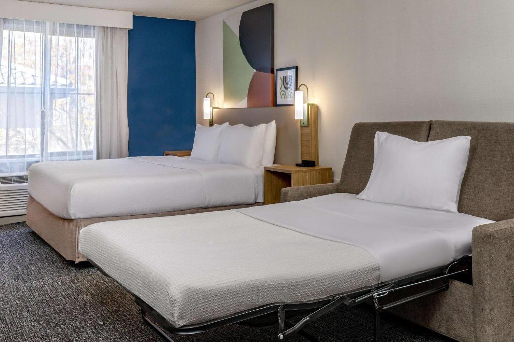 a hotel room with two beds and a chair at Spark by Hilton Denver International Airport in Denver