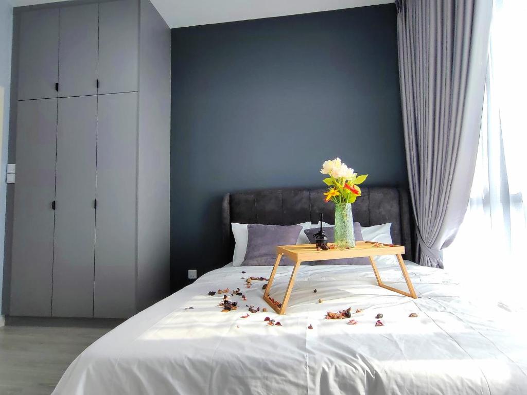 a bed with a table with flowers on it at Meta City Family Suite Equine Park IOI City Mall Serdang UPM in Seri Kembangan