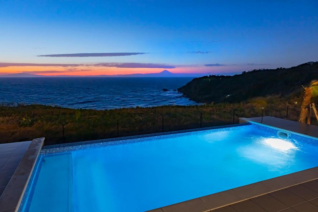 a swimming pool with a view of the ocean at dusk at The TRAVELERS Chateau Tateyama in Haraoka