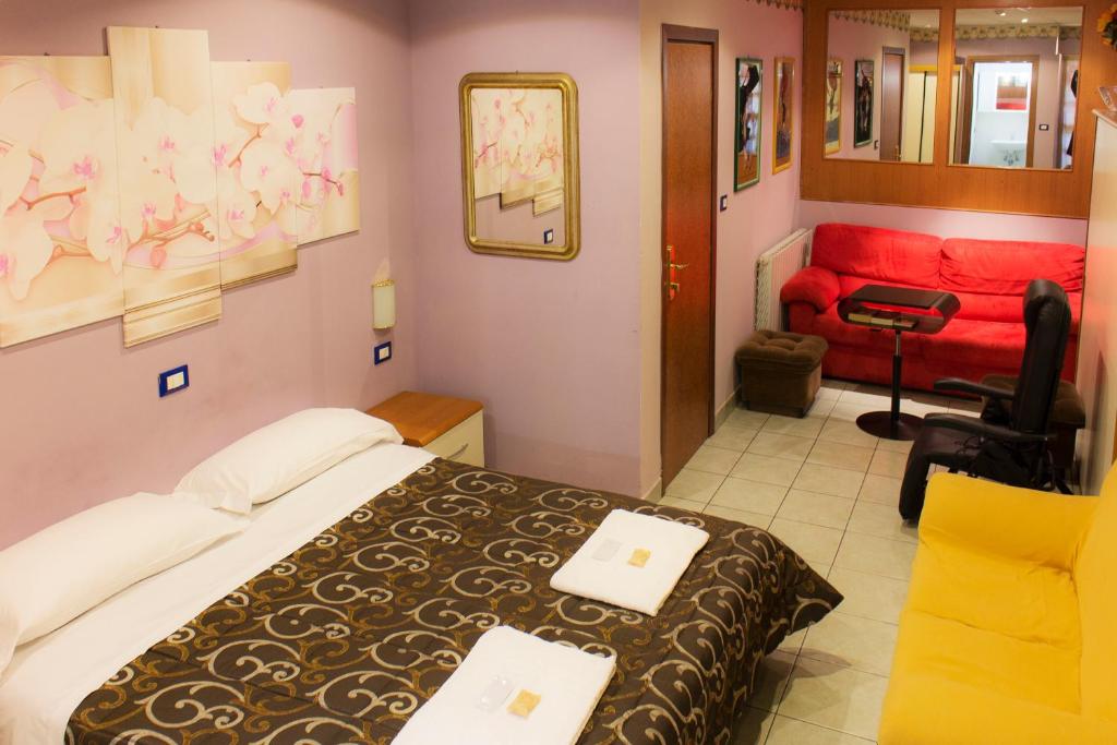 レッジョ・エミリアにあるHotel Saint Lorenzのベッドルーム1室(ベッド1台、赤いソファ付)