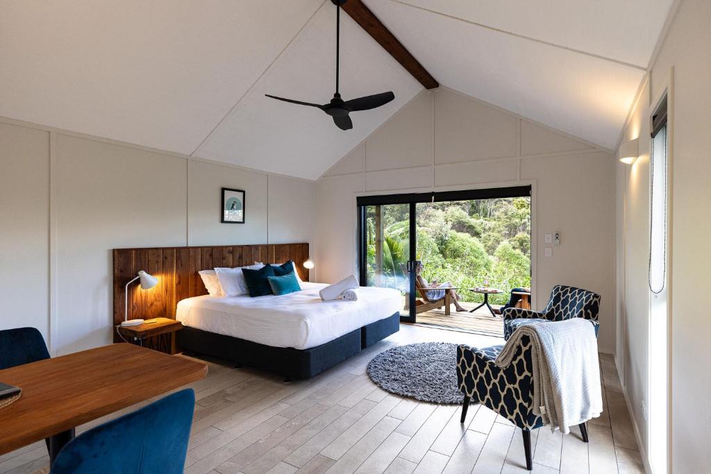 a bedroom with a bed and a table and chairs at The Hideout in Mangawhai