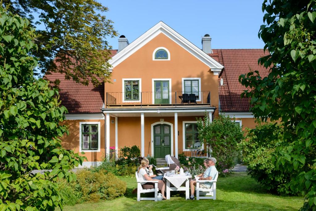 deux personnes assises à une table devant une maison dans l'établissement Gamla Brukshandeln Bed&Breakfast, à Lövstabruk