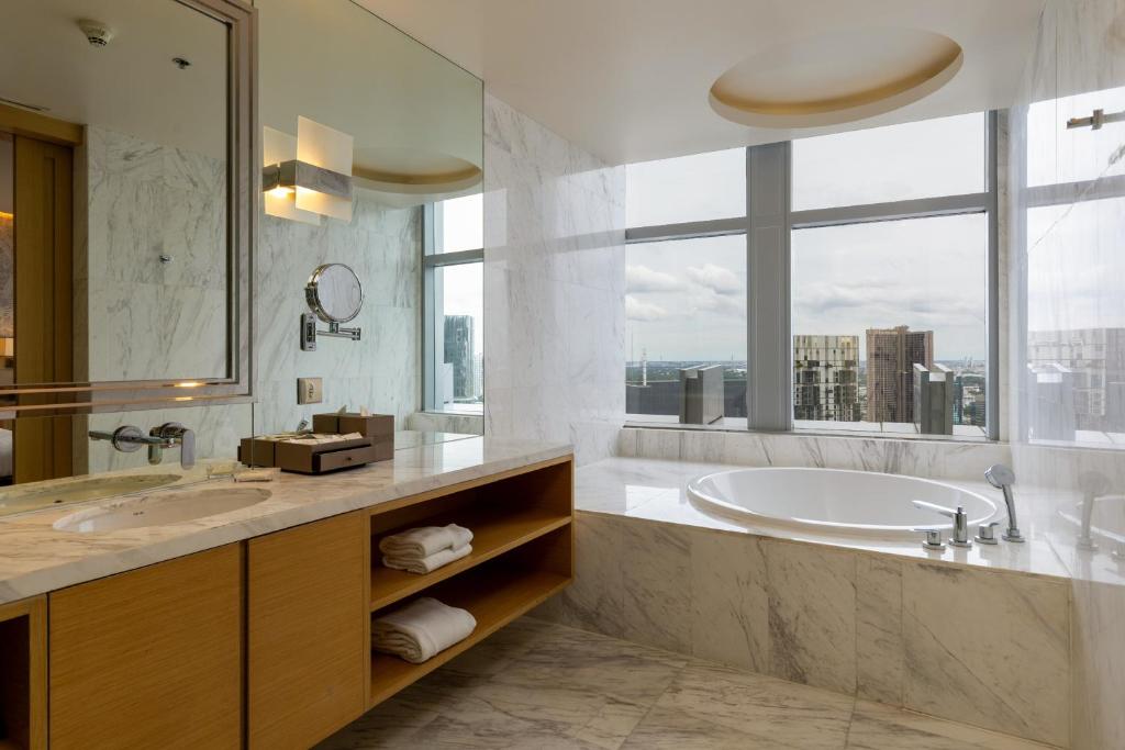 a bathroom with a tub and a sink and a window at Bangkok Marriott Hotel Sukhumvit in Bangkok