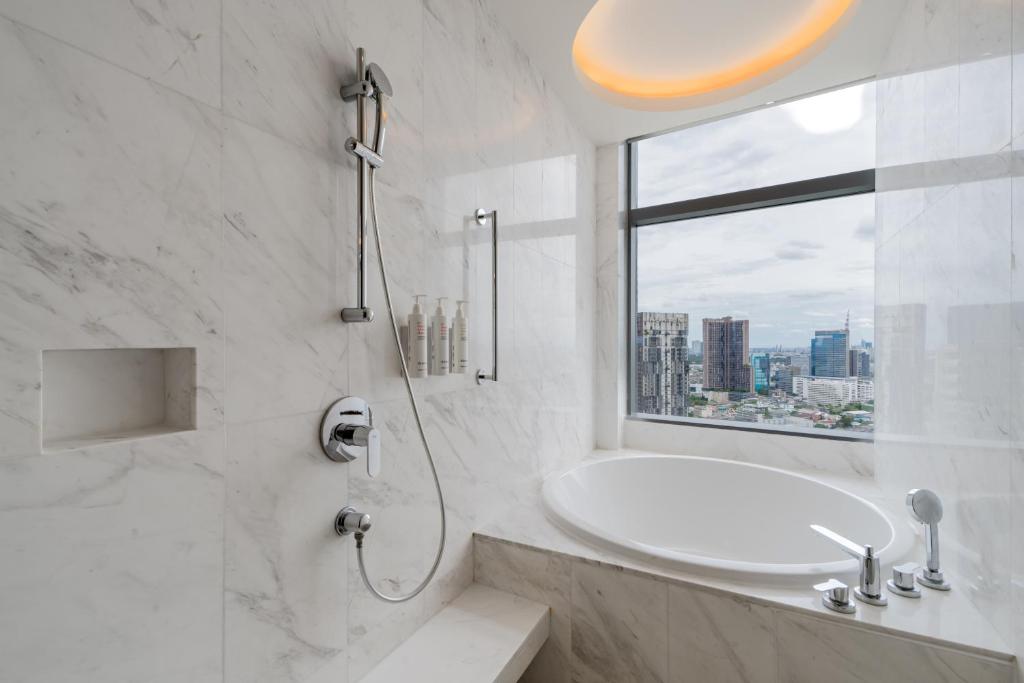 a white bathroom with a shower and a sink at Bangkok Marriott Hotel Sukhumvit in Bangkok