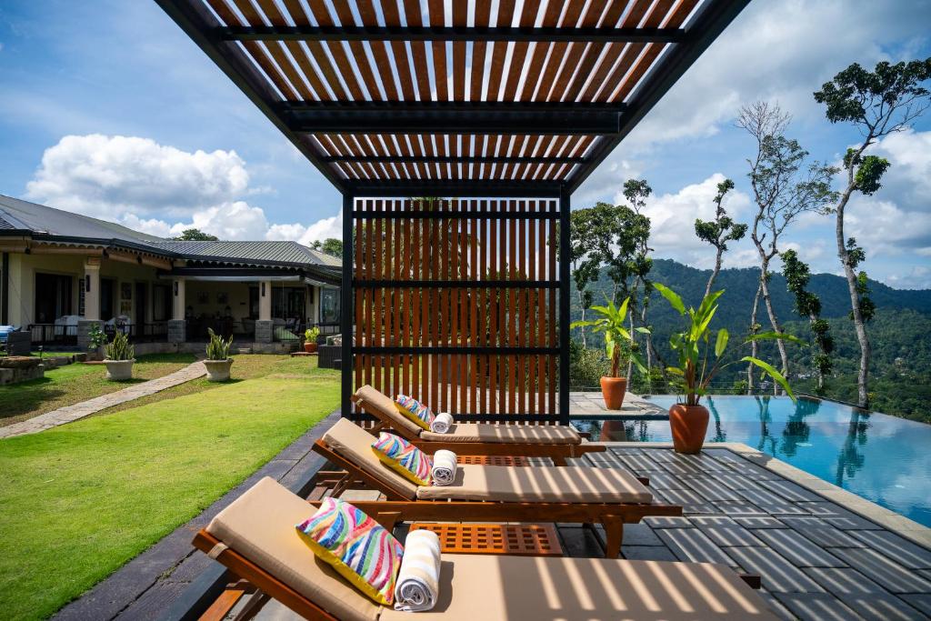 a patio with lounge chairs and a swimming pool at Riverdale Bungalow - Film Location For 'Bridge On The River Kwai' in Kandy