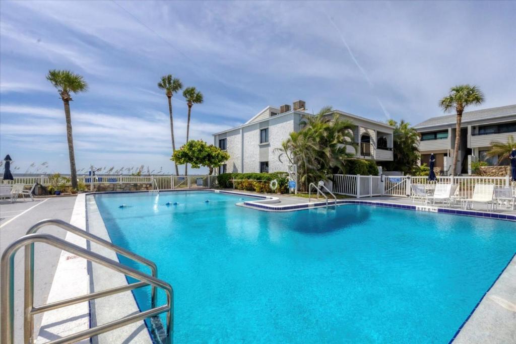 a large blue swimming pool with palm trees and a building at Beachside Bliss: Sarasota County Condo 1006 Awaits in Venice