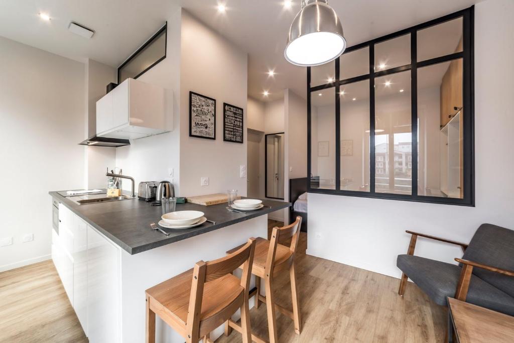 une cuisine et un salon avec une table et des chaises dans l'établissement Le petit Barret du 8ème AIL, à Lyon