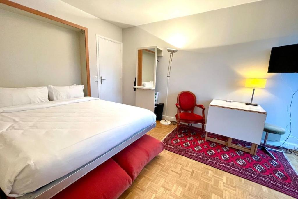 une chambre avec un grand lit et une chaise rouge dans l'établissement Parc Monceau - Chez Amélie, à Paris