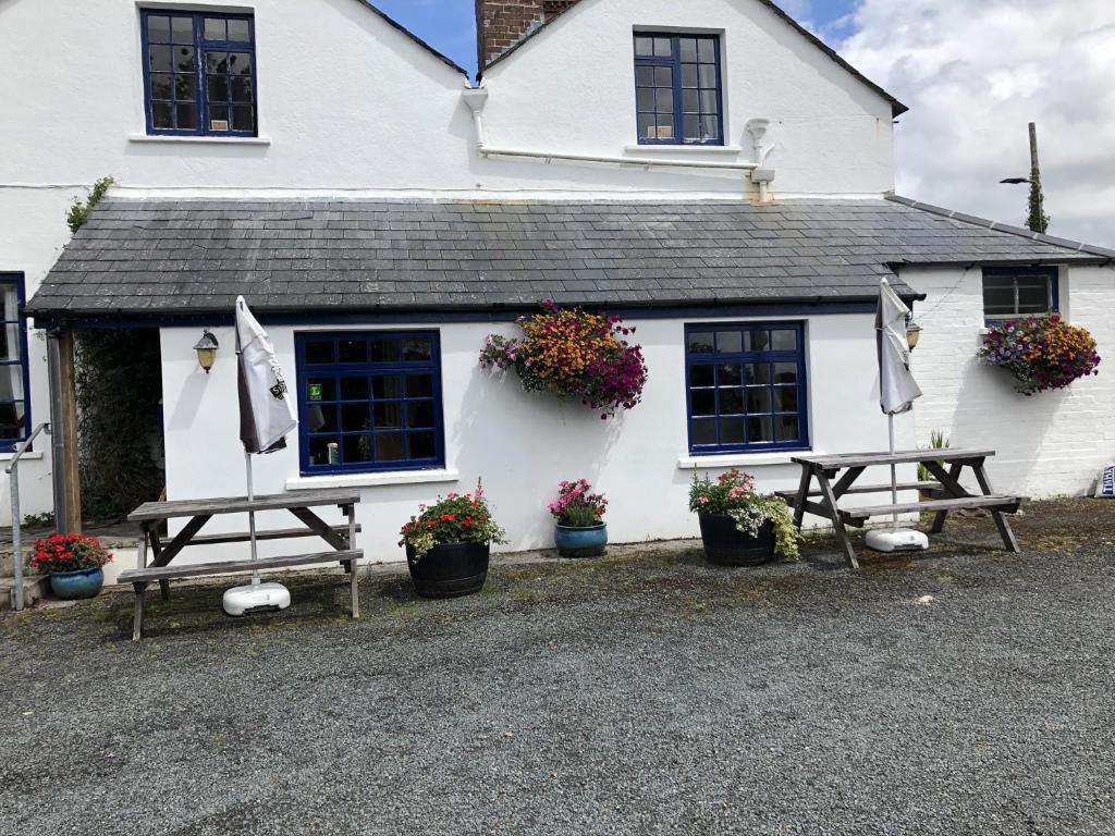 un edificio blanco con dos mesas de picnic delante de él en Blue Lion Inn, en Lewdown