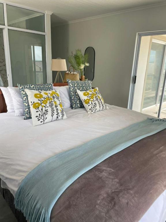 a large bed with many pillows on it at Calypso beach holiday in Langebaan