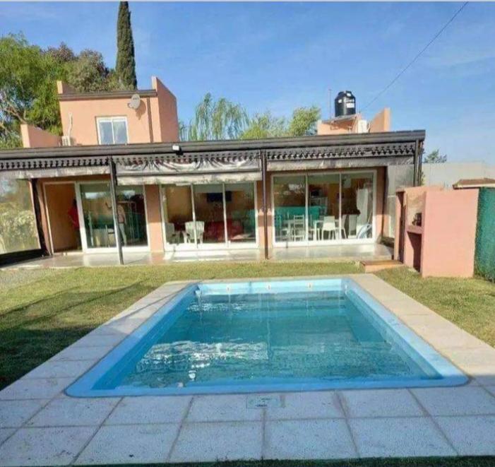 una casa con piscina delante de una casa en Casa quinta, en Carmen de Areco