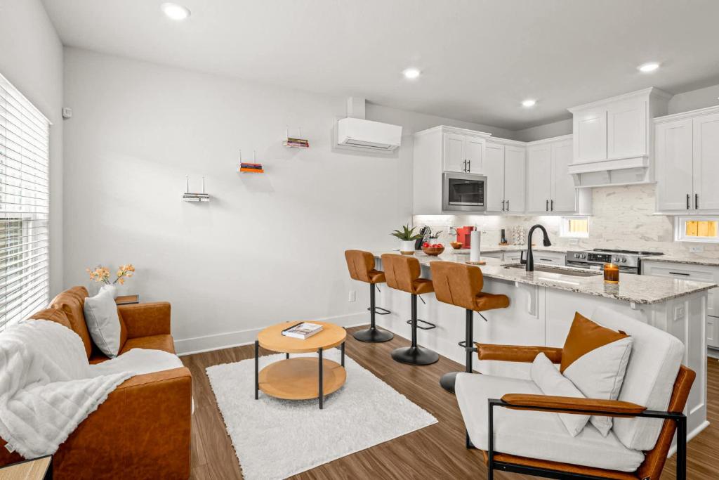a kitchen and living room with white cabinets at Stylish 2BR Home Near University of Arkansas in Fayetteville