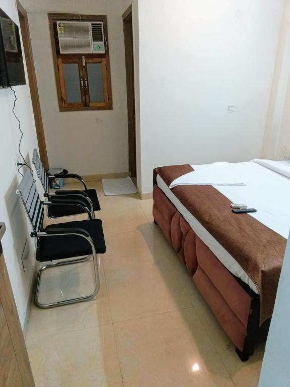 una camera con due letti e sedie in esso di Soooper Hotel a Gurgaon