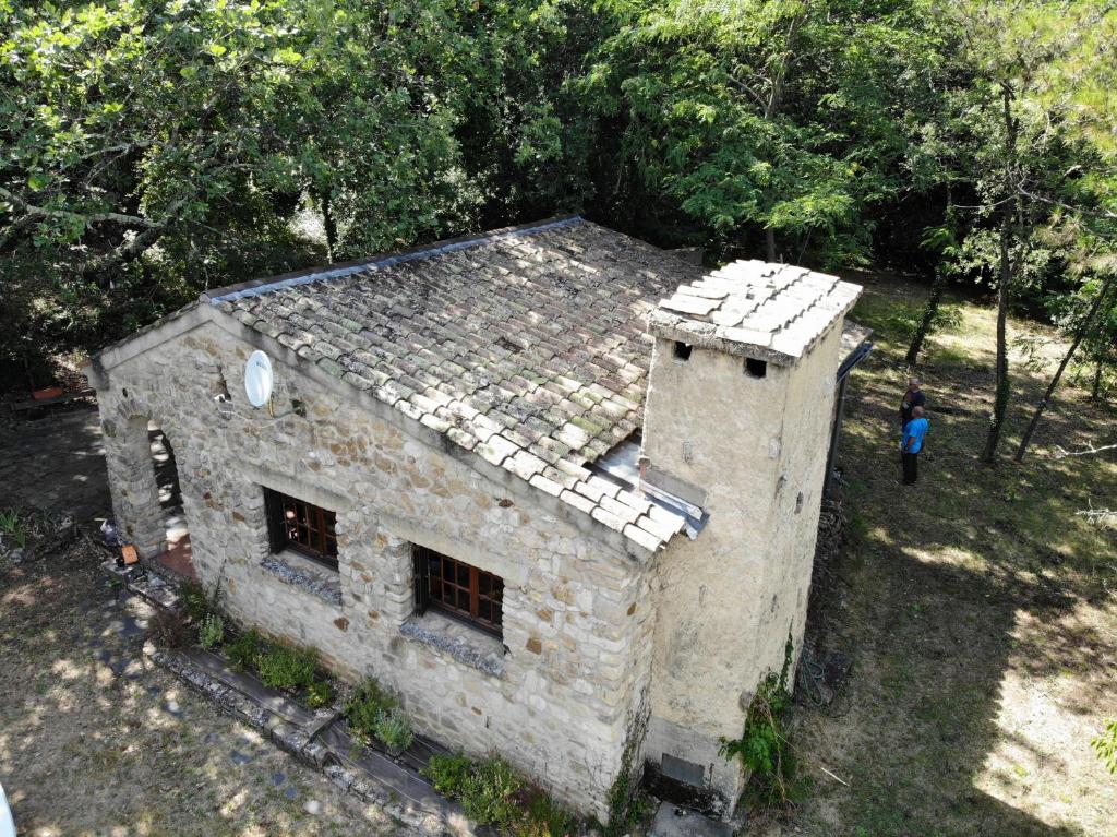 - un vieux bâtiment en pierre avec une personne debout à côté dans l'établissement maison de campagne, à La Roque-sur-Cèze