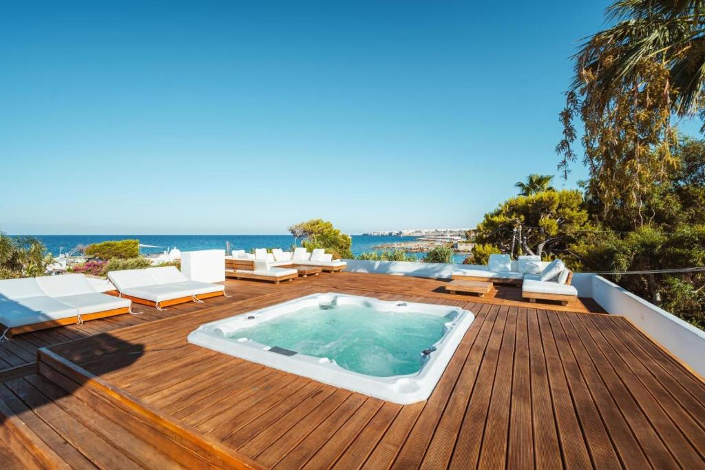 a hot tub on a deck with chairs and the ocean at MareLuxe & Pool in Polignano a Mare