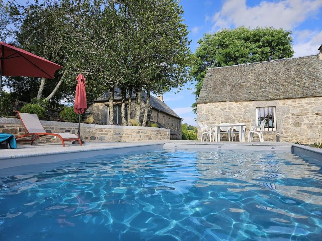 une piscine devant une maison avec un bâtiment dans l'établissement La Borie de Peyrot, à Cassuéjouls