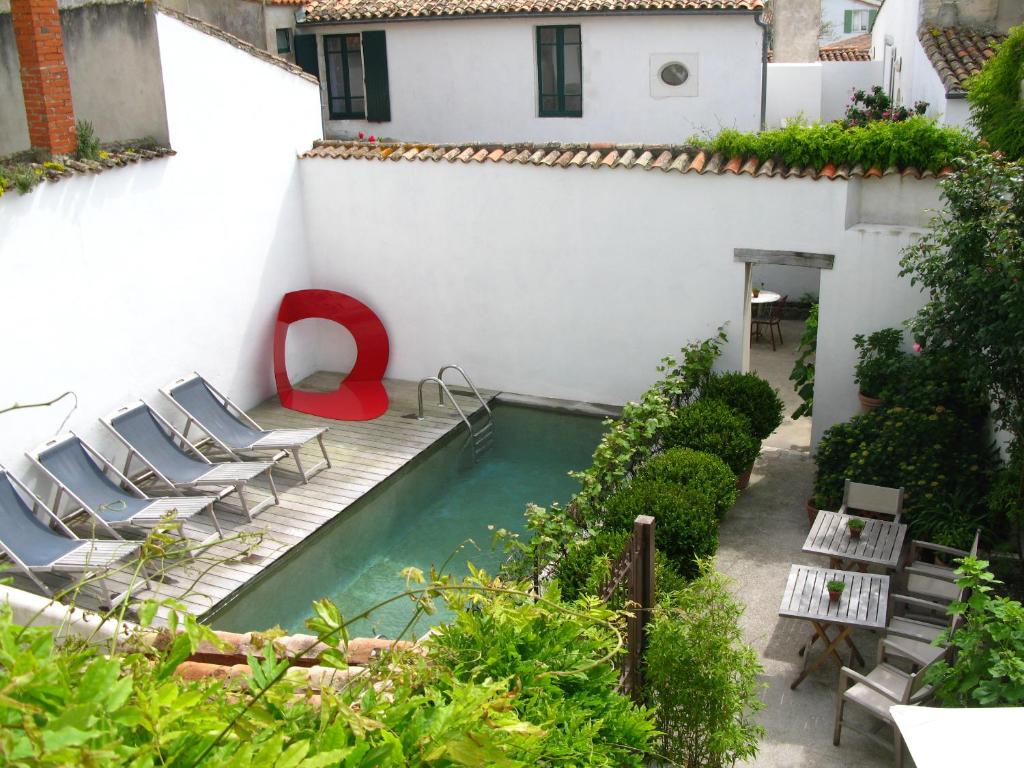 un patio con sillas y una piscina en un edificio en Hôtel Le Sénéchal en Ars-en-Ré