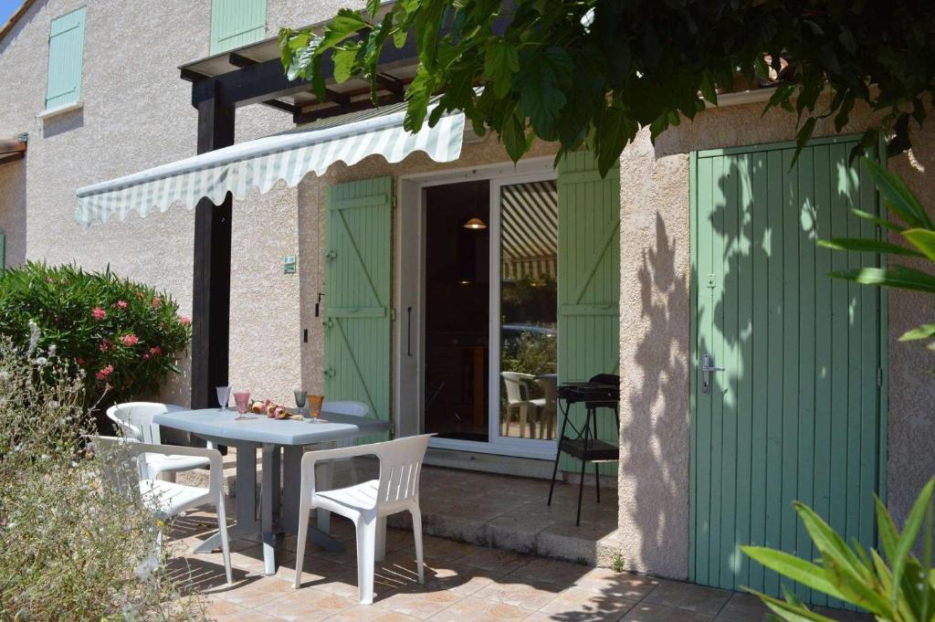 d'une terrasse avec une table, des chaises et une porte verte. dans l'établissement SP340-008 Mais 2 pièces mezz 6 couchages SAINT PIERRE LA MER, à Saint Pierre La Mer