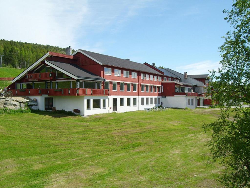 a large red and white building on a grass field at Lia Fjellhotell in Geilo