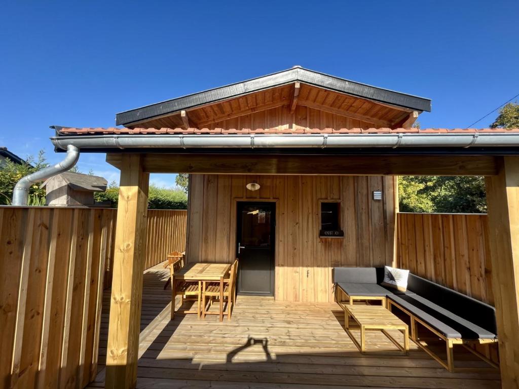 a pavilion with a bench and a table on a deck at La cabane du Broustic in Andernos-les-Bains