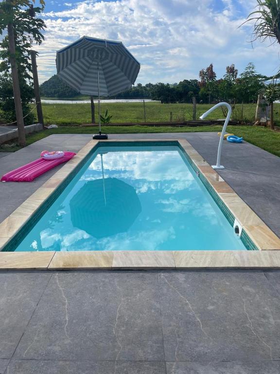 a swimming pool with an umbrella and an umbrella at Casa com Piscina na Represa de Carlópolis in Carlópolis