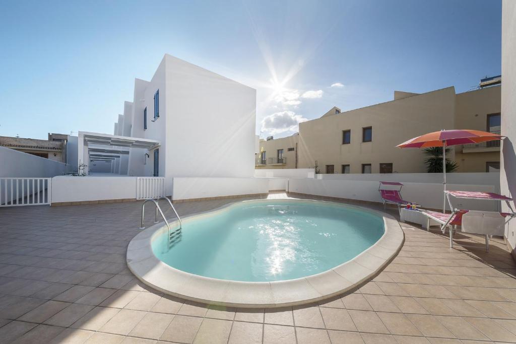 a swimming pool on a patio with an umbrella at BluSide Home & Suite in San Vito lo Capo
