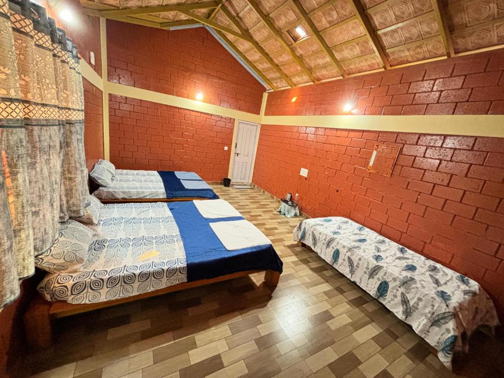 a bedroom with two beds and a brick wall at Coorg hill in Somvārpet