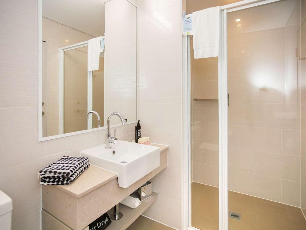 bagno bianco con lavandino e doccia di Ibis Styles The Entrance a The Entrance