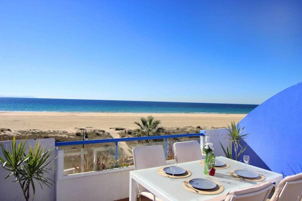 Biały stół z krzesłami i widokiem na plażę w obiekcie Livingtarifa Apartamento Paradise w mieście Tarifa