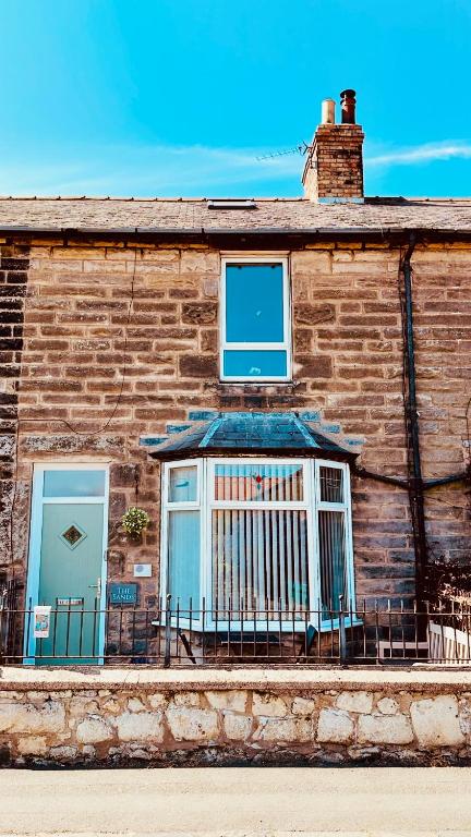 a brick building with a window and a balcony at HomeDecor Cottages - The Sands Cottage in Seahouses