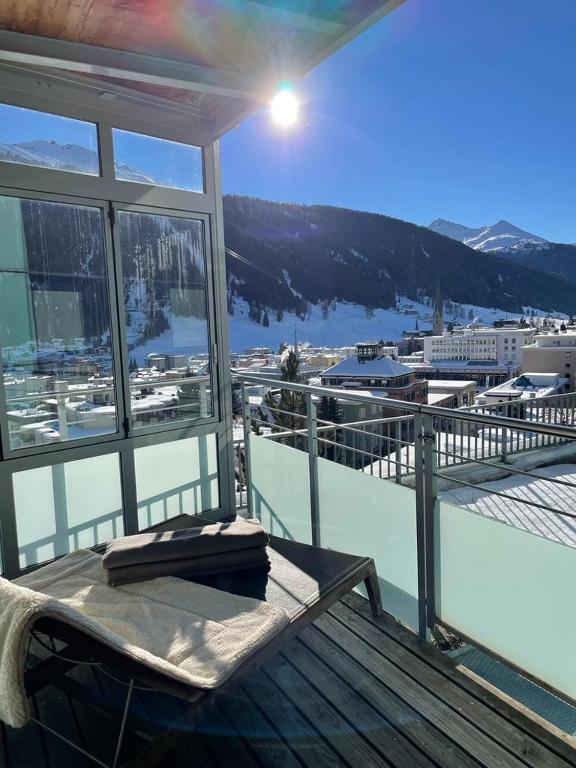 un balcon avec un banc et une vue sur une ville dans l'établissement Davos Luxury Apartment - 5 Min walking to Congress Center, à Davos