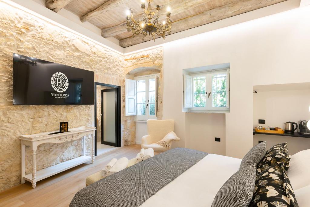 a bedroom with a bed and a tv on the wall at Pedra Bianca Luxury Rooms in Cagliari