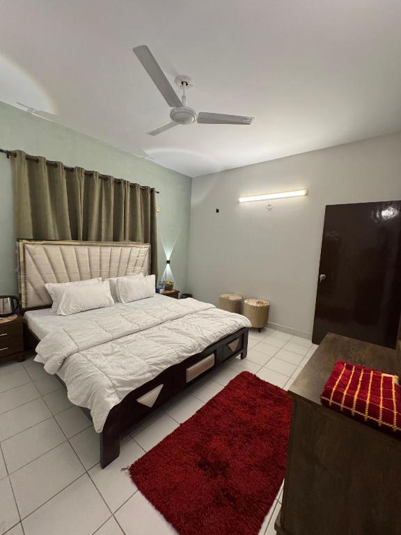 a bedroom with a large bed and a ceiling fan at Rosewood Cottage in Karachi