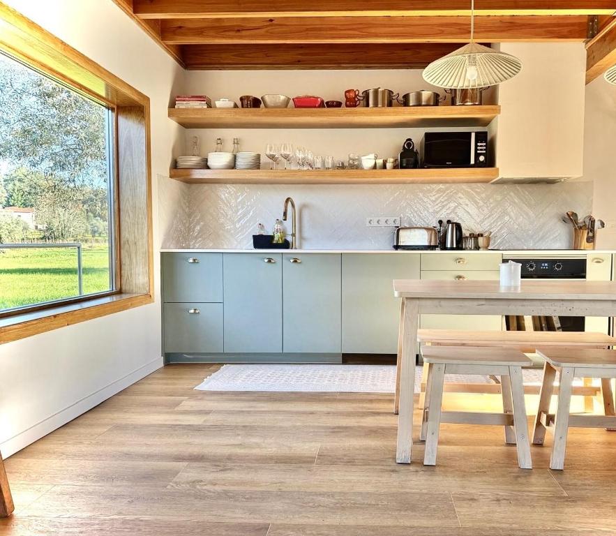 uma cozinha com armrios azuis, uma mesa e uma janela em Casa do Rio Alva em Arganil