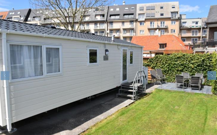 una piccola casa bianca con sedie e un cortile di Camping Astrid a Bredene