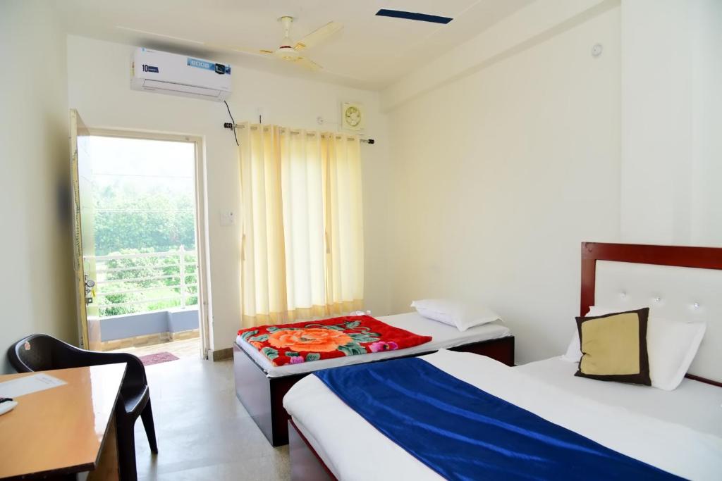 ein Zimmer mit zwei Betten und einem Tisch und einem Fenster in der Unterkunft Hotel Mount View in Haldwani-Kathgodam