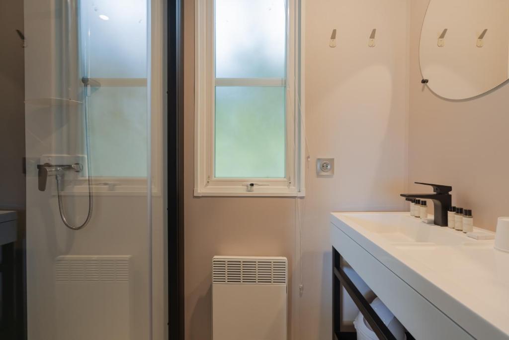 a bathroom with a shower and a sink and a window at Camping Les Grenettes in Sainte-Marie-de-Ré