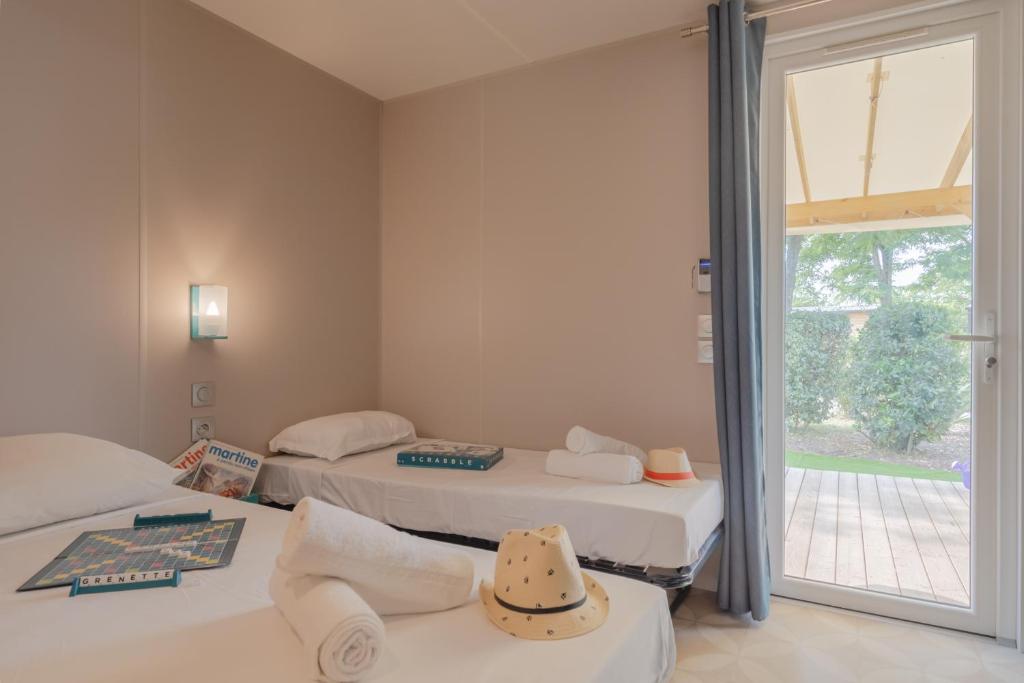 two beds in a room with a window at Camping Les Grenettes in Sainte-Marie-de-Ré